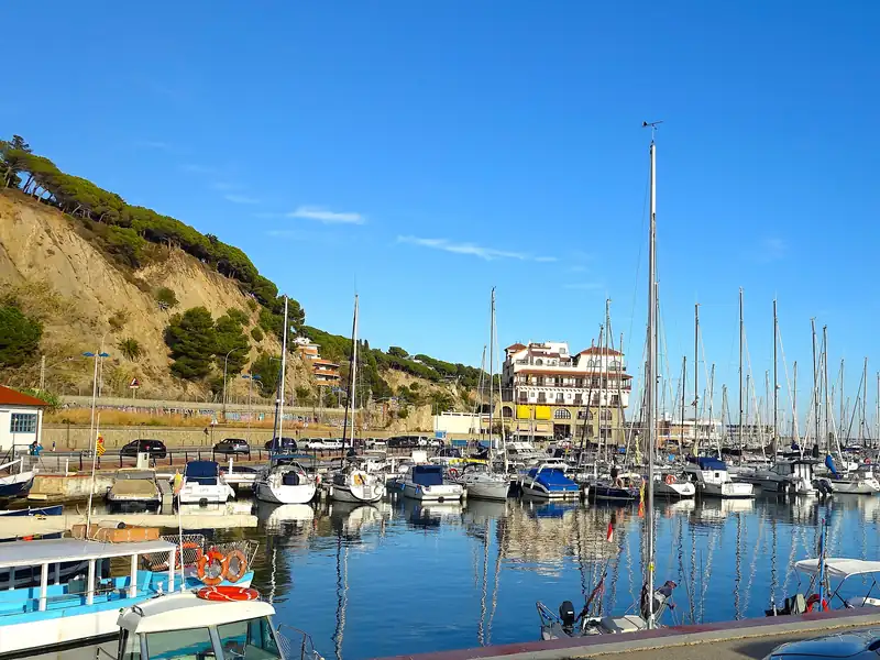 Puerto deportivo de Arenys de Mar con veleros y la colina de pinos