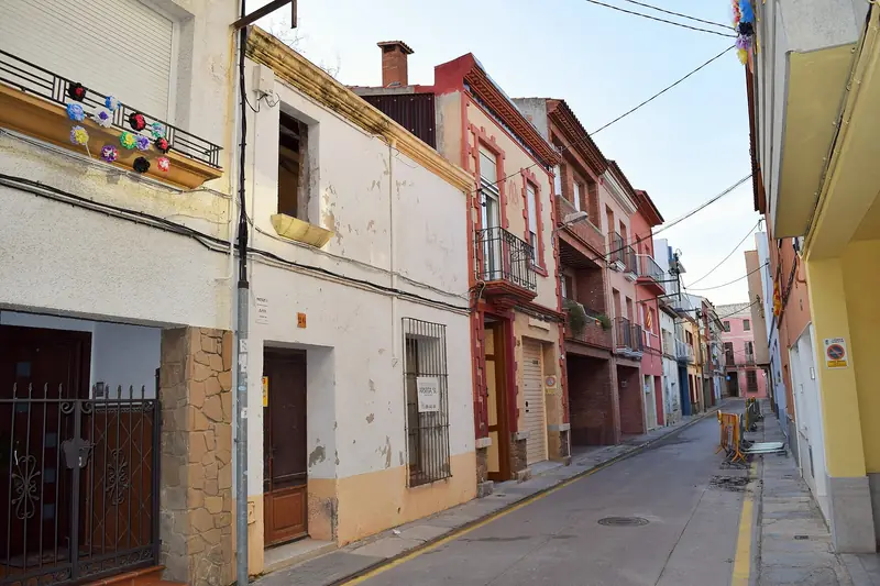 Calle de casas de dos plantas con balcones de hierro en Malgrat de Mar